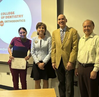 Dr. Suzanne Abreu receives an AAOF RAA grant certificate while standing with Dean Susan Rowan, Dr. Peter Durbin and Dr. Budi Kusnoto, all smiling.
                  