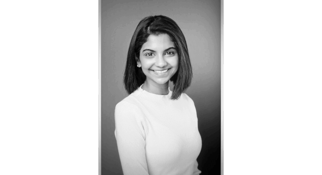 Black and white portrait of Dr. Pheba Abraham smiling wearing a light sweater against a plain background.