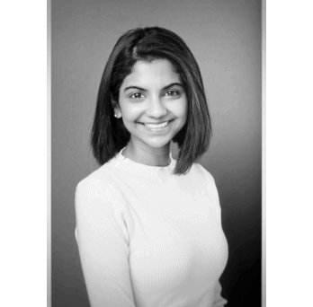 Black and white portrait of Dr. Pheba Abraham smiling wearing a light sweater against a plain background.
                  
